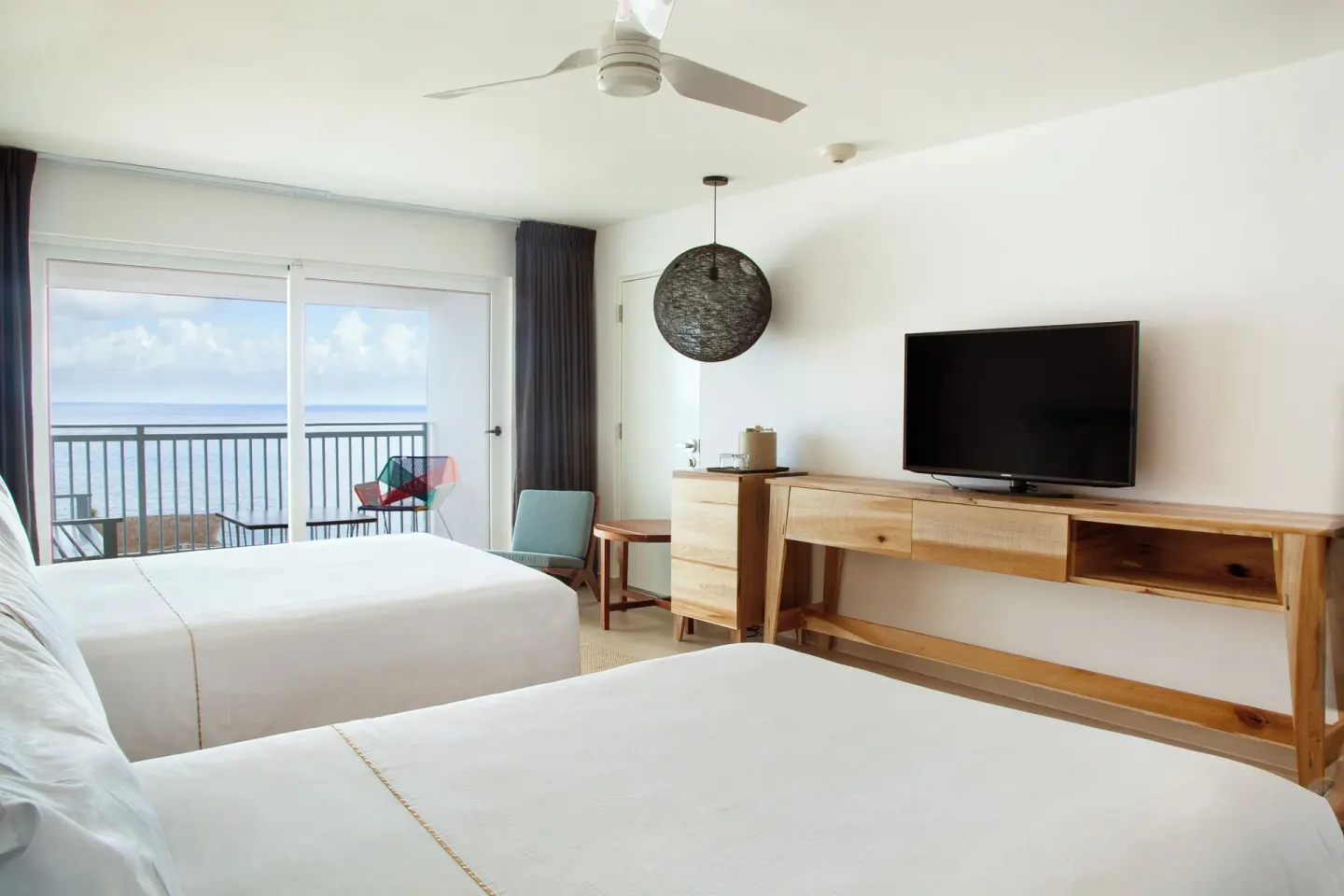 Deluxe ocean view room with two beds and balcony seating at Fiesta Americana Cozumel.
