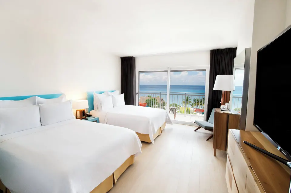 Bright deluxe ocean view room with two beds and TV at Fiesta Americana Cozumel.
