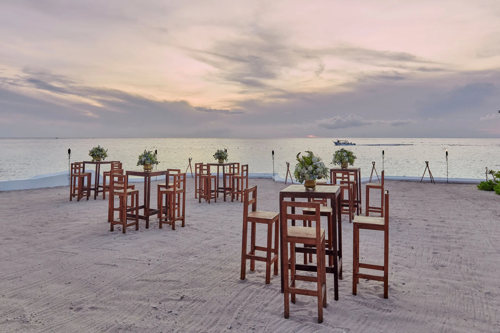 Beach cocktail tables set on sand at sunset at Fiesta Americana Cozumel.