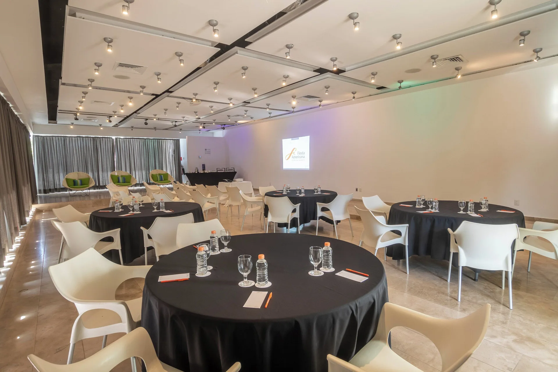 Conference room with round tables and a projected presentation at Fiesta Americana Cozumel.