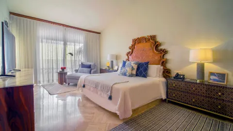 Guest room with king bed, ornate headboard, and balcony curtains at Fiesta Americana Puerto Vallarta & Spa.