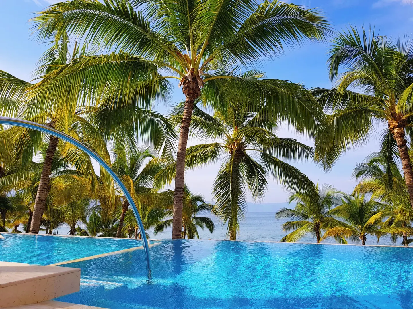 Infinity-style pool edge with palms and ocean at Fiesta Americana Puerto Vallarta & Spa.