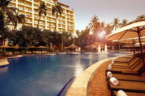 Pool loungers with towels and hotel tower at Fiesta Americana Puerto Vallarta & Spa.