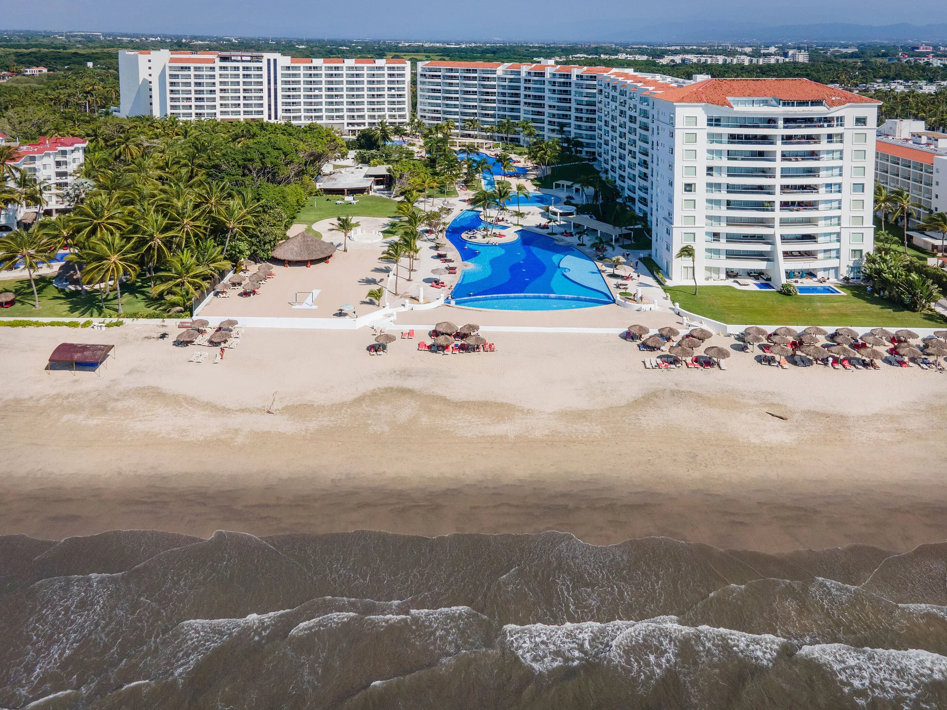 Beachfront aerial of Fiesta Americana Riviera Nayarit Resort & Spa with pools, palapas, and surf.