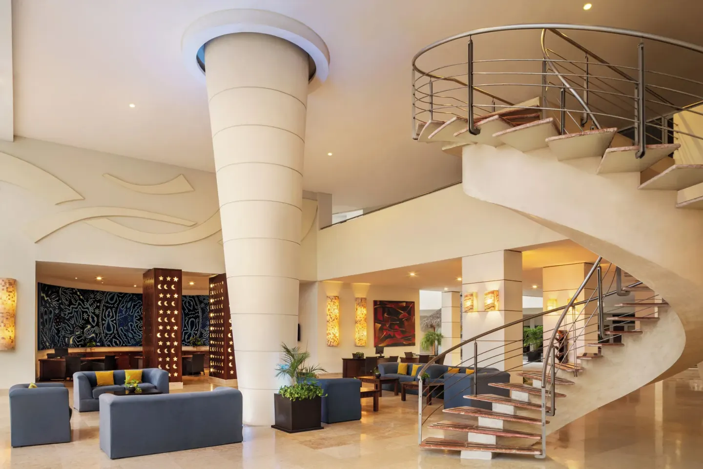 Lobby lounge at Fiesta Americana Riviera Nayarit Resort & Spa with sofas, columns and a curved staircase.