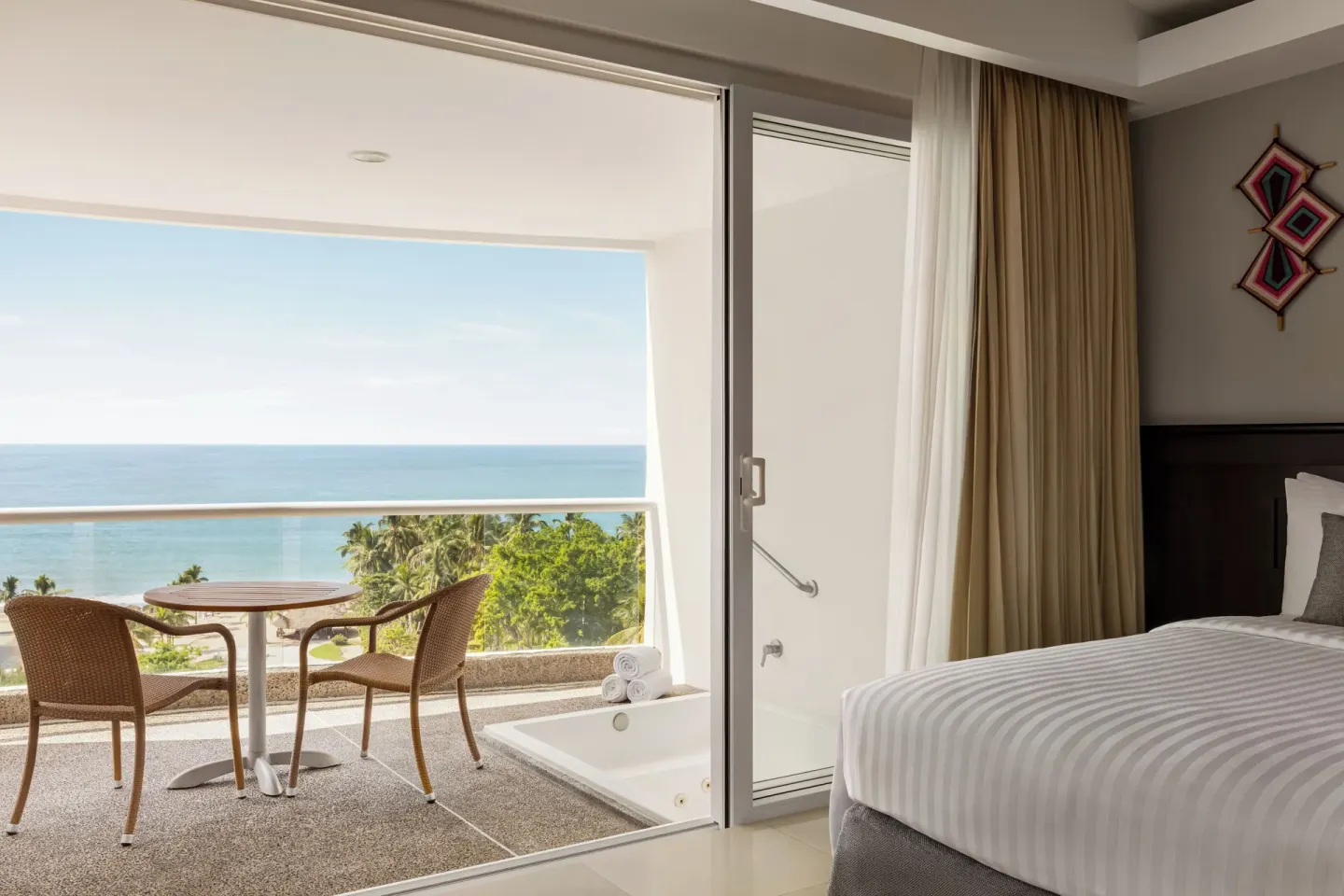 Guest room with bed, balcony seating, and ocean view at Fiesta Americana Riviera Nayarit Resort & Spa.
