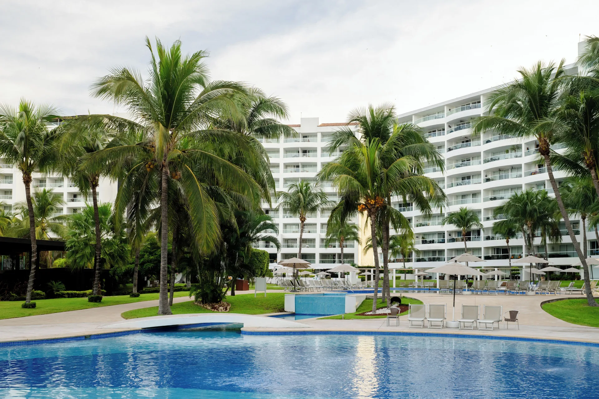 Pool area with palms and resort buildings at Fiesta Americana Riviera Nayarit Resort & Spa.