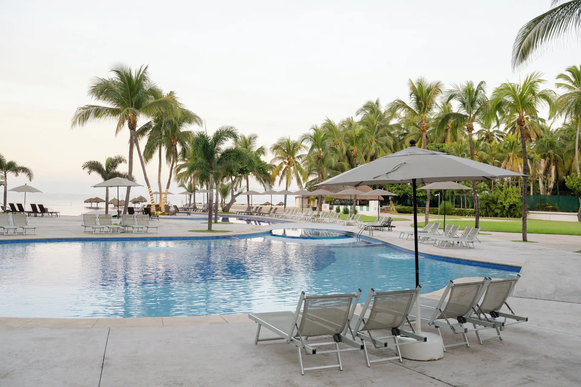 Poolside loungers and palms by the water at Fiesta Americana Riviera Nayarit Resort & Spa.