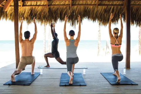Guests practice yoga beneath a beachfront palapa at Finest Playa Mujeres.