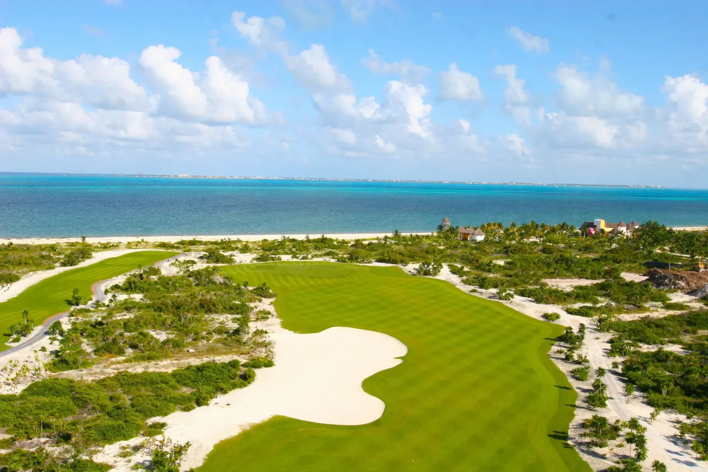 Aerial view of a green golf fairway beside the Caribbean at Finest Playa Mujeres.