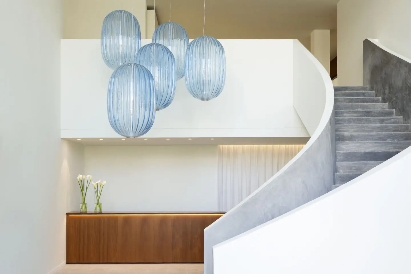 Curved lobby staircase and blue pendant lights at Finest Playa Mujeres.