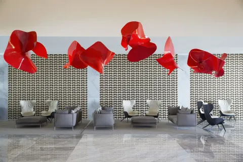 Lobby lounge with red hanging sculptures and patterned wall at Finest Playa Mujeres.