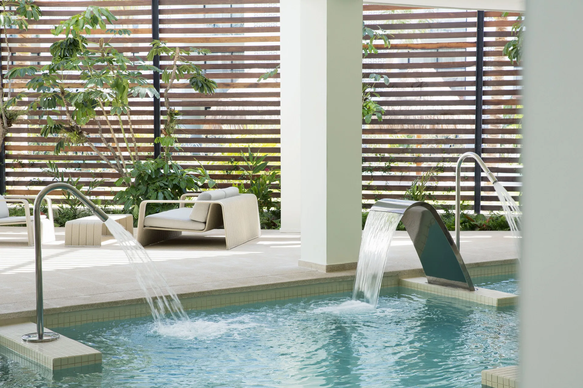 Spa pool with water jets, lounge chairs and wood privacy screens at Finest Playa Mujeres.