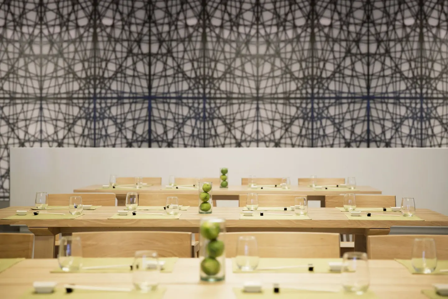 Modern dining room with pale wood tables and patterned wall art at Finest Playa Mujeres.