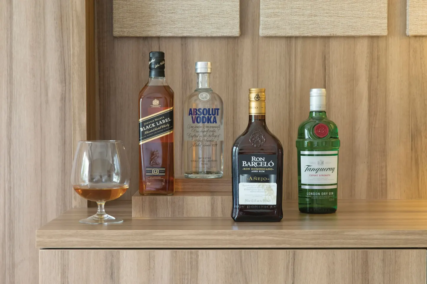 In-suite liquor selection on a wood cabinet at Finest Playa Mujeres.