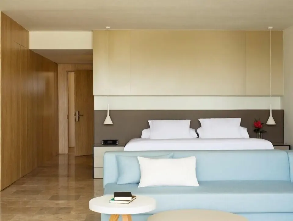 Junior Suite Spa or Pool View king bed behind a blue sofa at Finest Playa Mujeres.