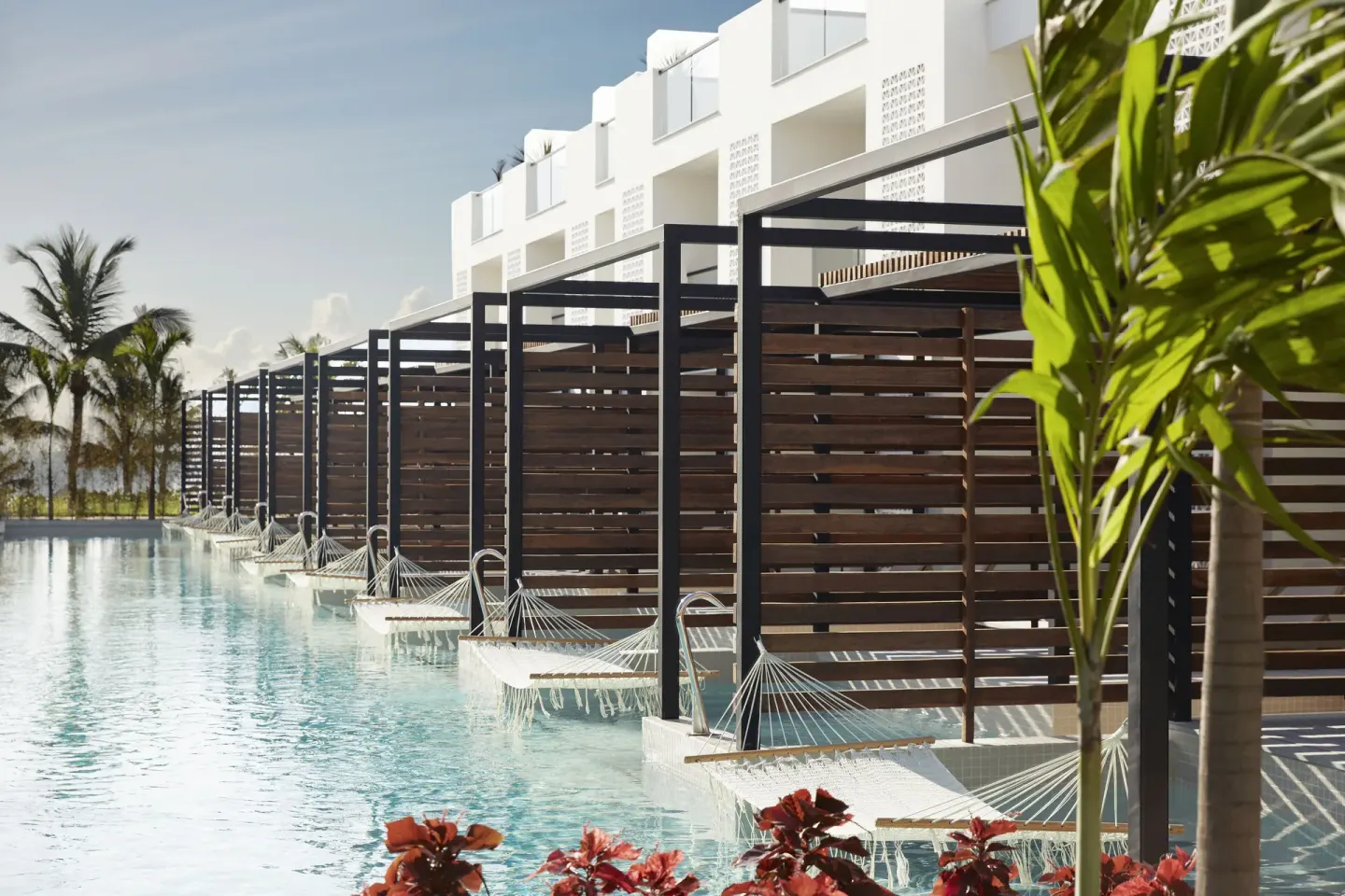 Row of Junior Swim-Up Suite terraces with hammocks and pool access at Finest Playa Mujeres.