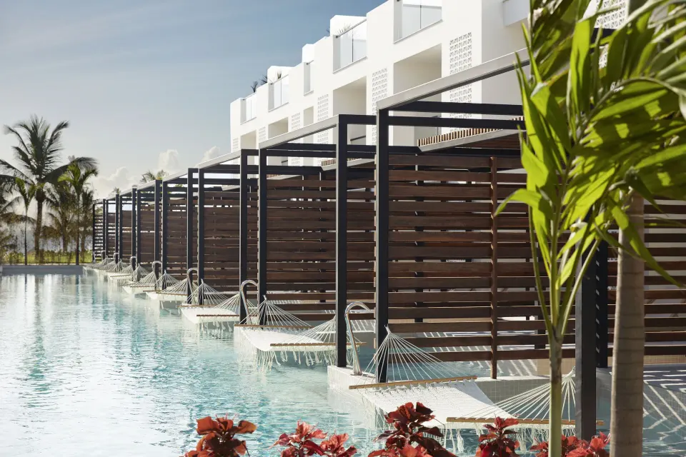 Row of Junior Swim-Up Suite terraces with hammocks and pool access at Finest Playa Mujeres.