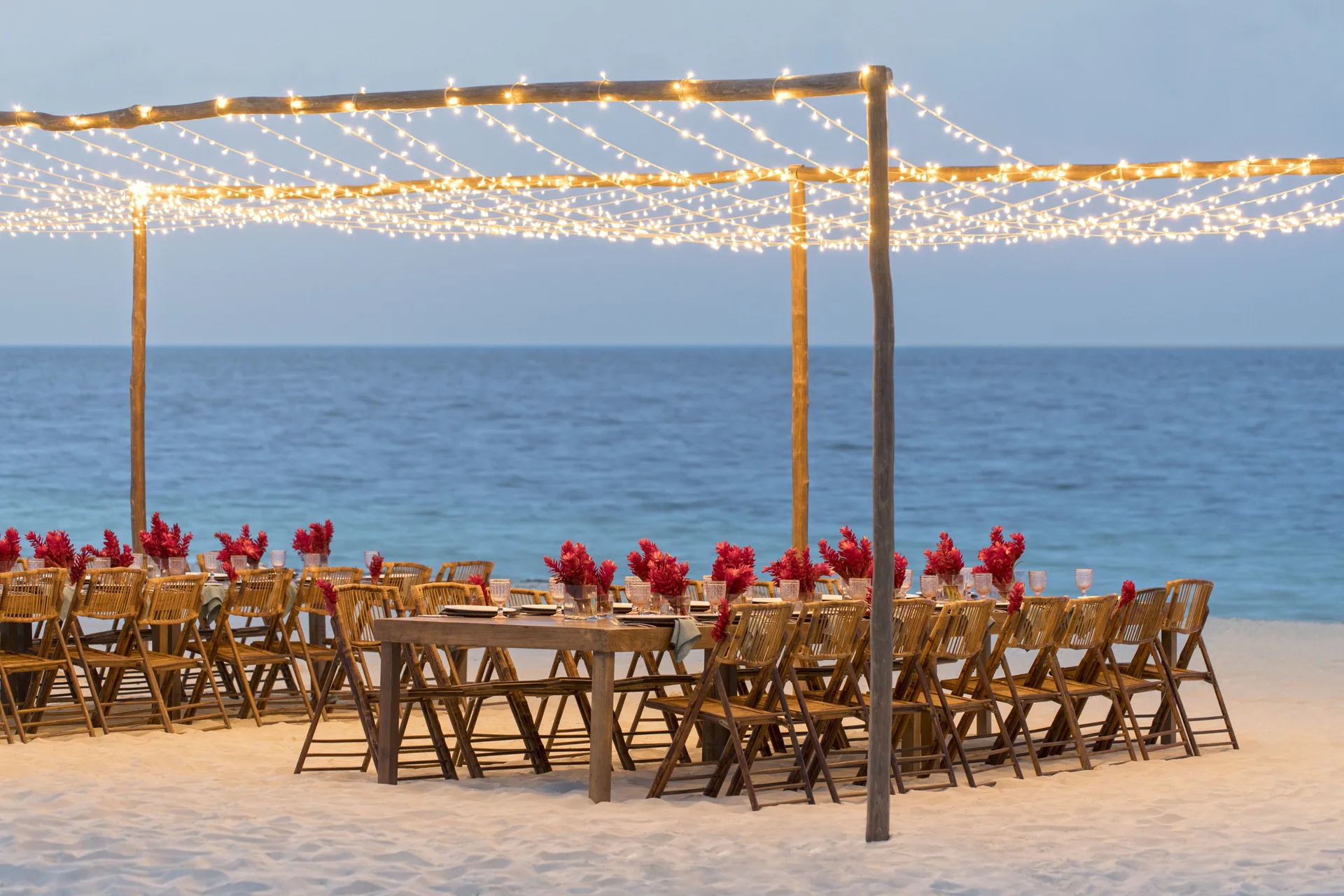 Beach event tables under string lights by the ocean at Finest Playa Mujeres.