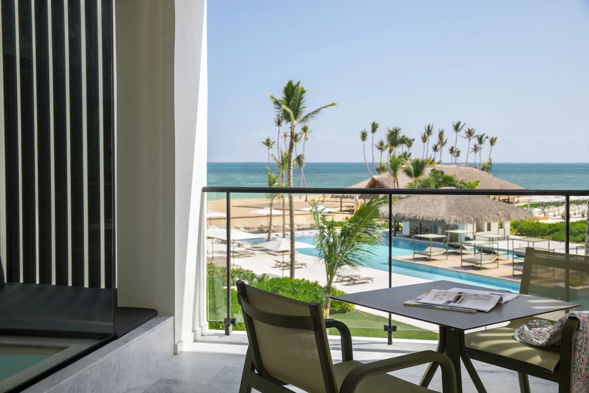 Balcony seating with pool, palms, beach, and ocean views at Finest Punta Cana.
