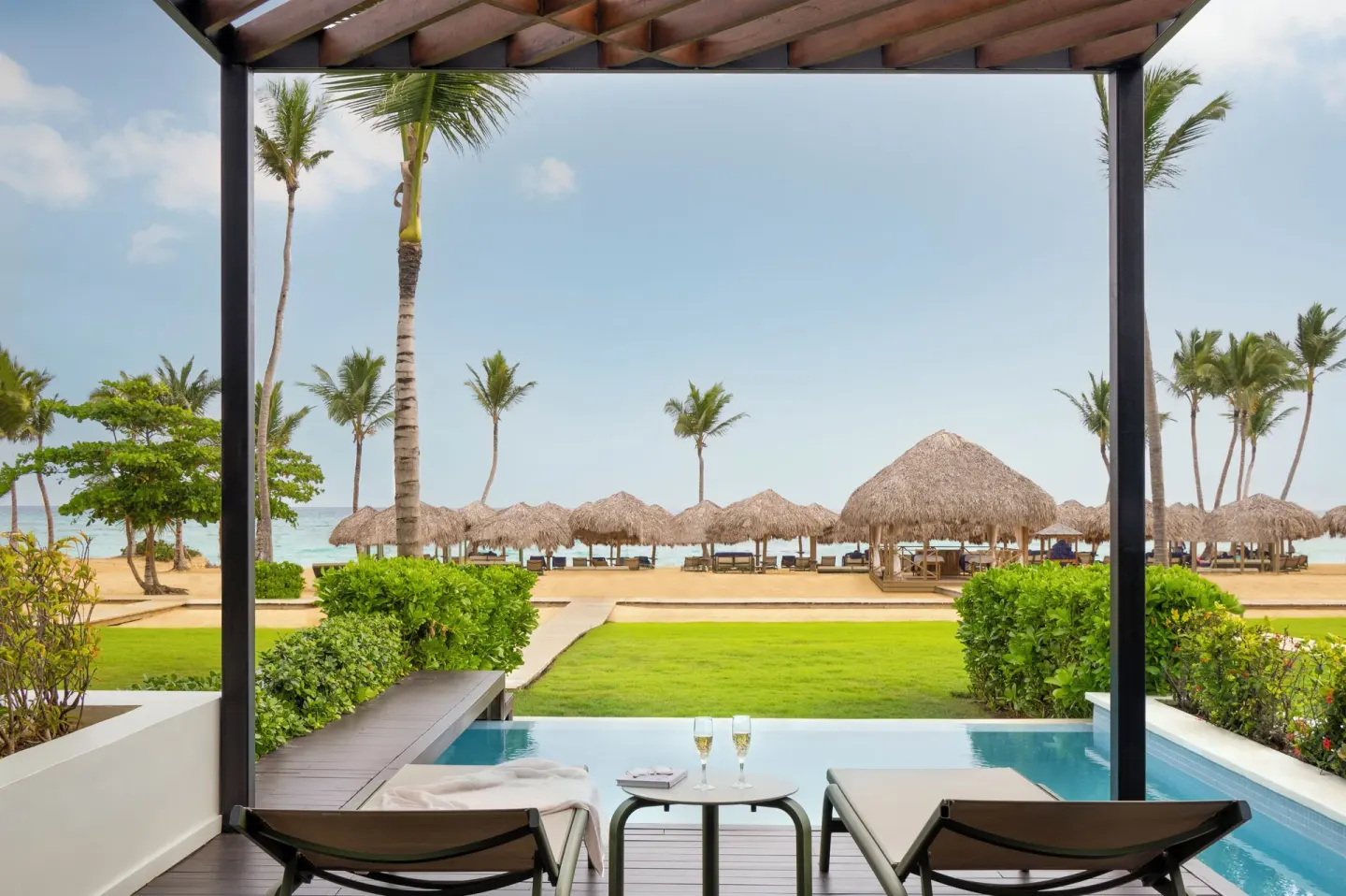 Beachfront swim-up terrace with loungers and palapas at Finest Punta Cana.