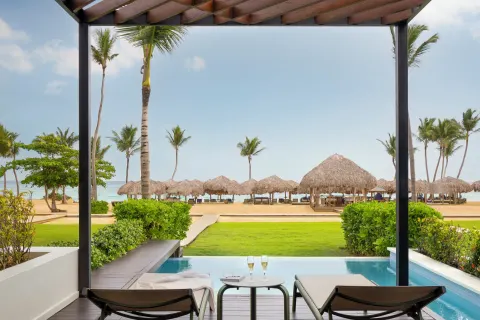 Beachfront swim-up terrace with loungers and palapas at Finest Punta Cana.