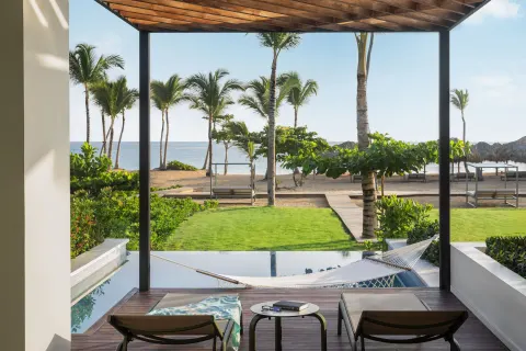 Terrace with loungers, hammock, plunge pool, lawn, palms, and beach beyond at Finest Punta Cana.