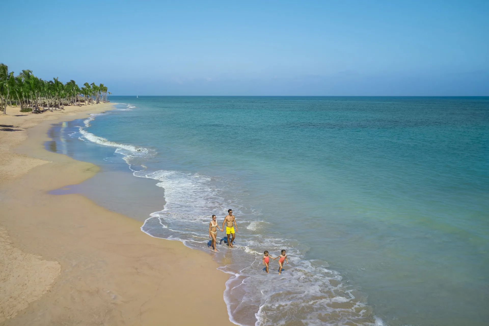 Family walking in the surf on the beach at Finest Punta Cana.