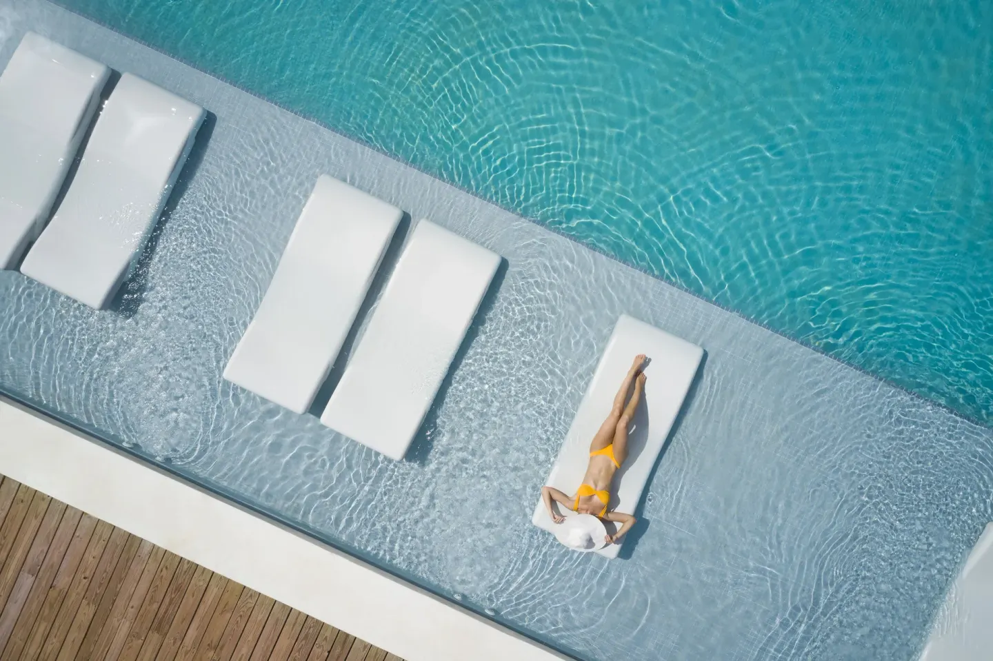 Overhead view of in-water loungers and a sunbather in a pool at Finest Punta Cana.