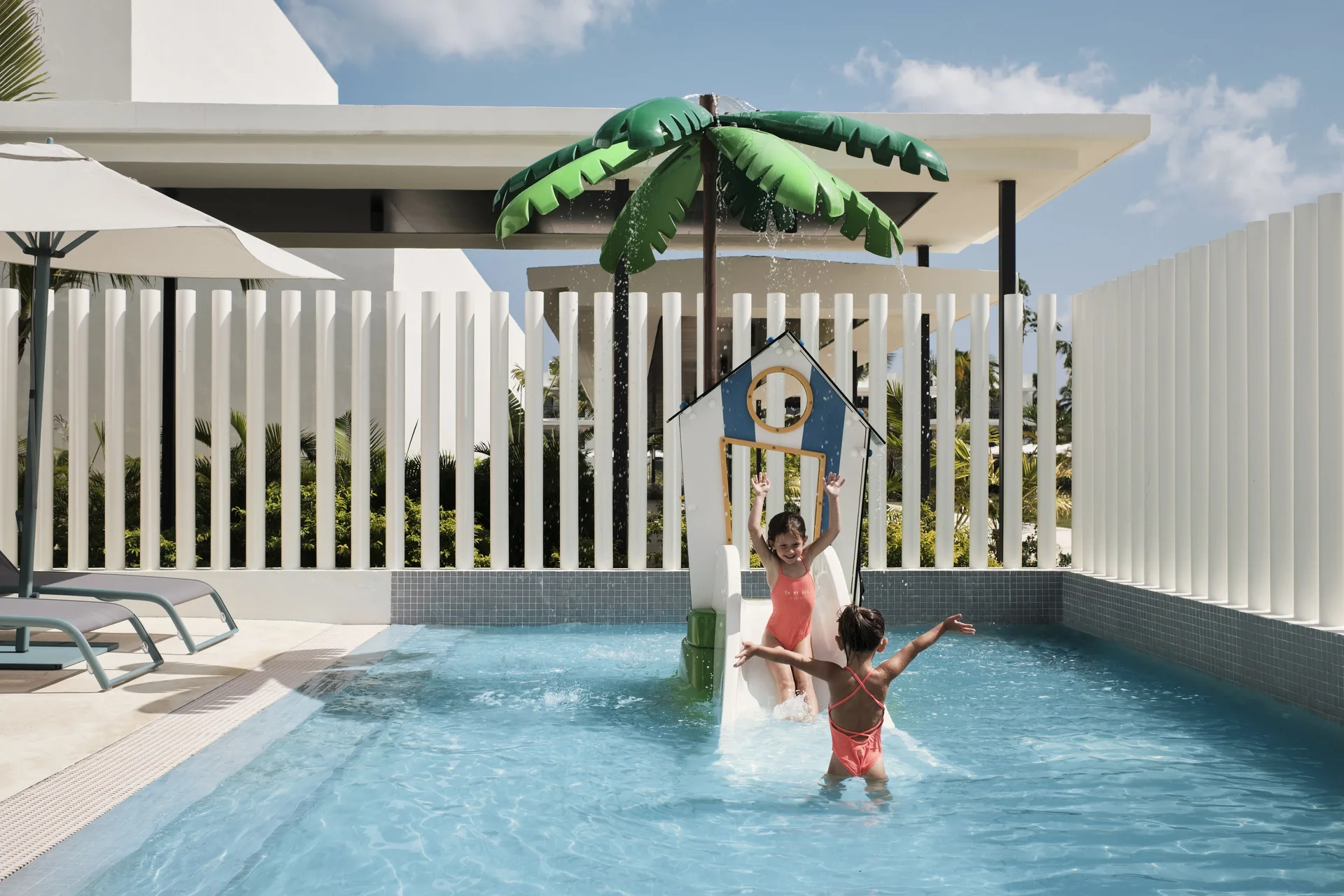 Children play in a small pool beneath a palm-shaped water feature at Finest Punta Cana.