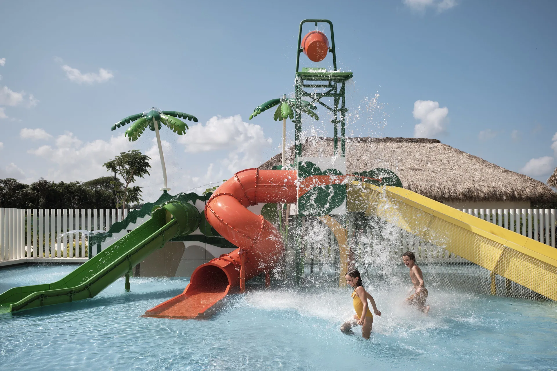 Children splash by colorful water slides and a tipping bucket at Finest Punta Cana.