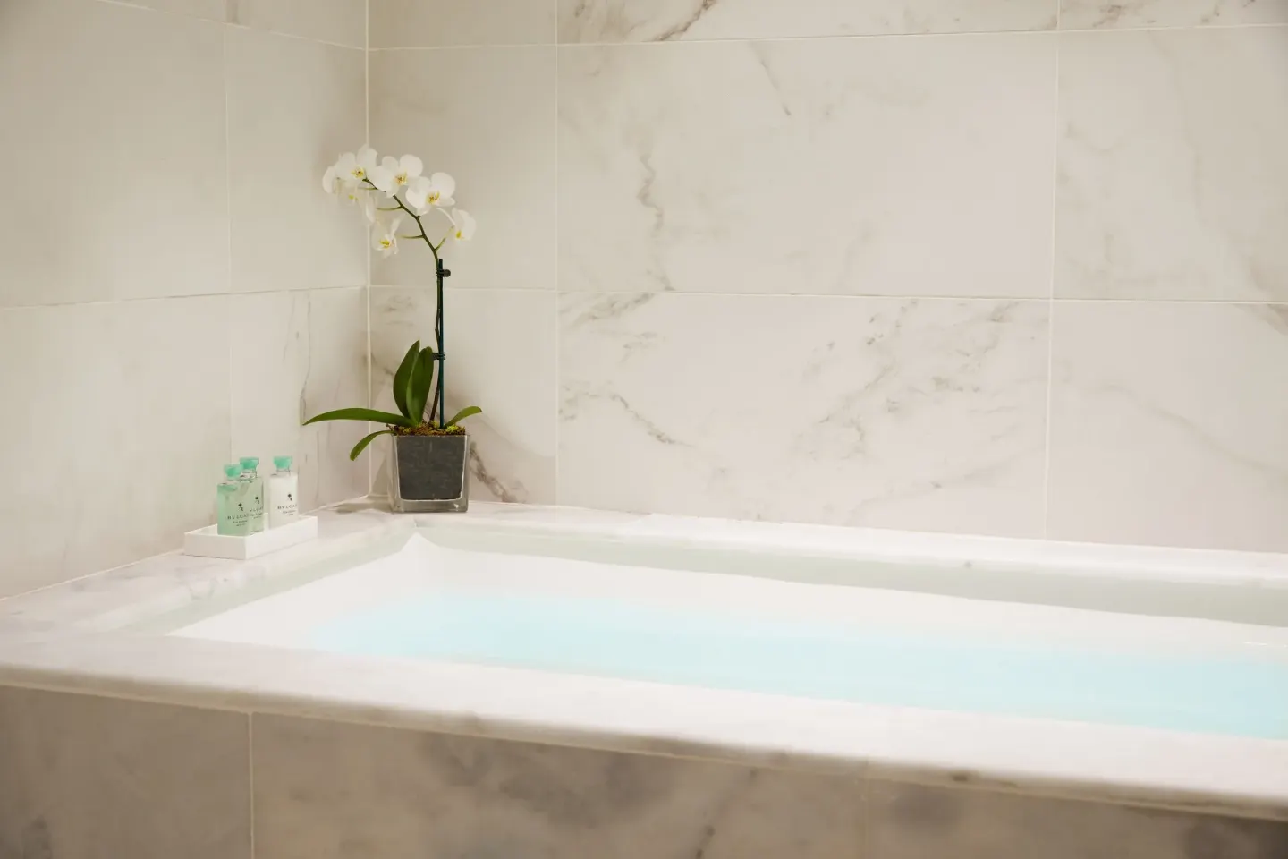 Marble bathroom tub with orchid and bath amenities at Finest Punta Cana.