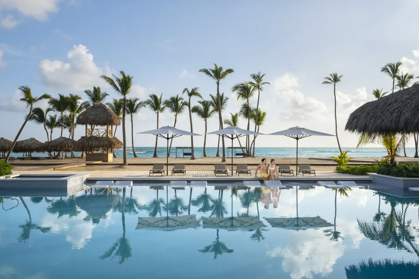 Infinity-edge pool reflecting palms, umbrellas, and the ocean at Finest Punta Cana.