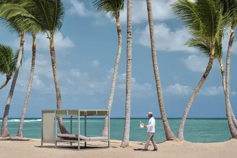 Palm-lined beach with a shaded daybed at Finest Punta Cana.