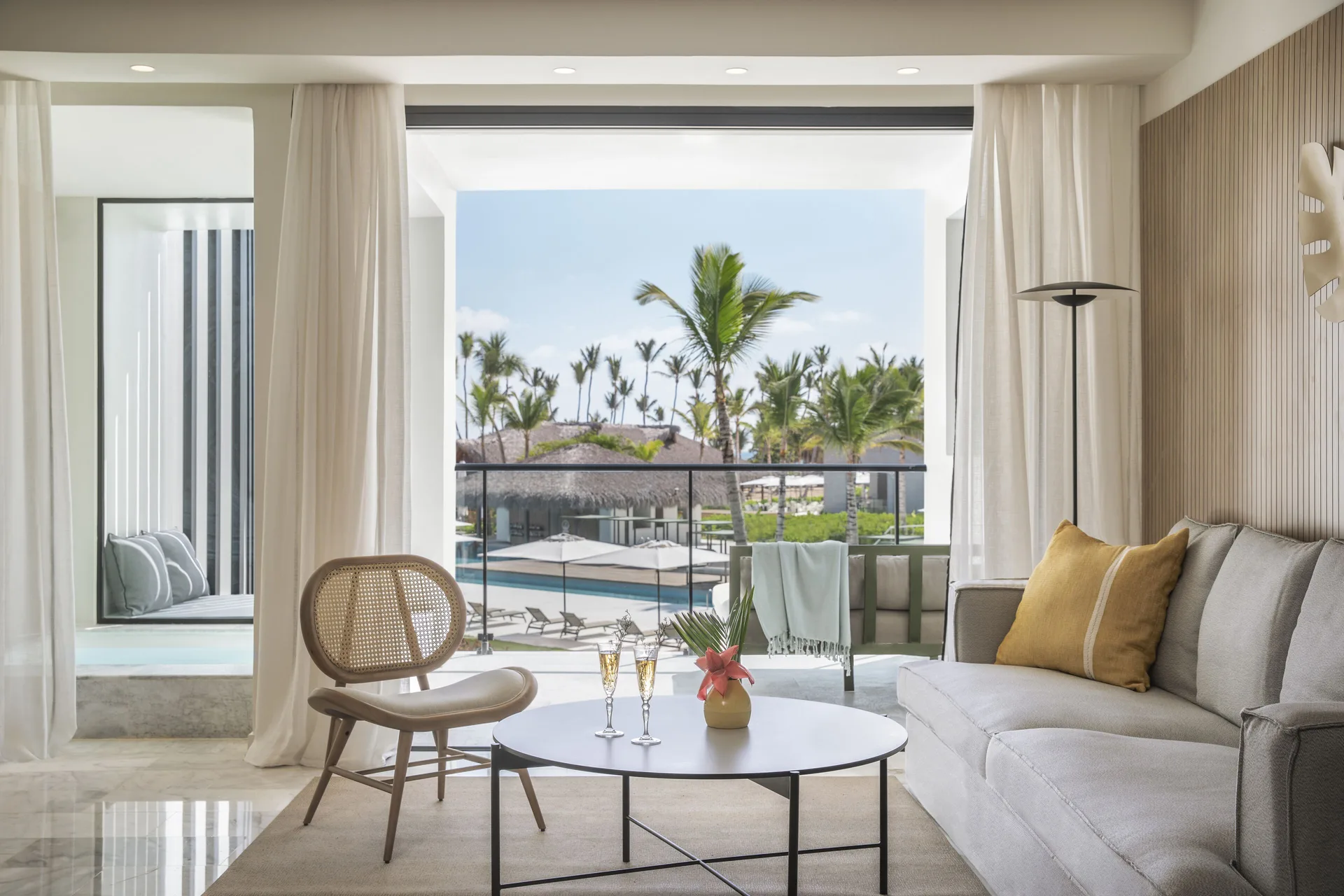 Suite sitting area with balcony view of pools and palms at Finest Punta Cana.
