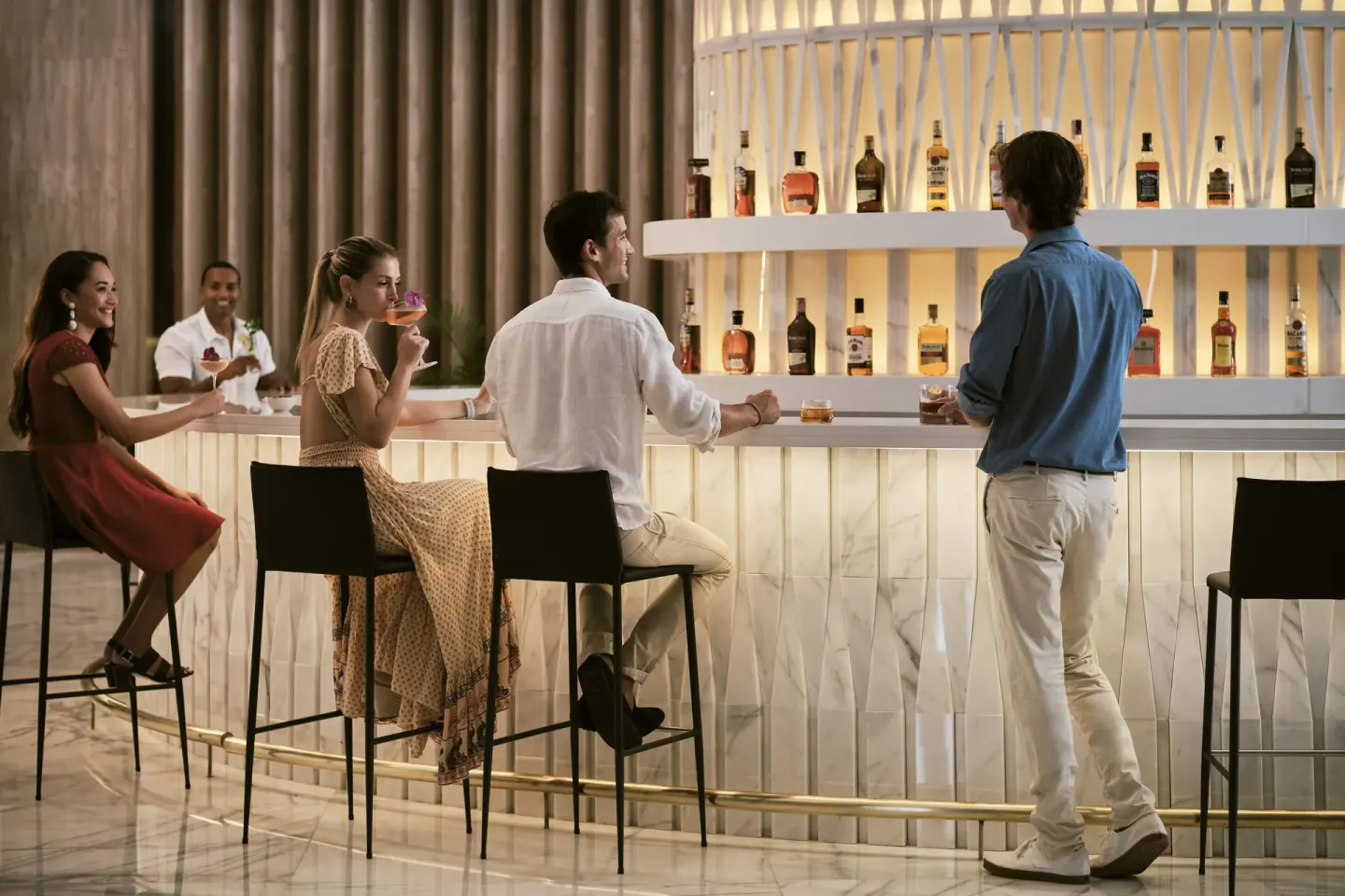 Guests seated at a glowing marble bar inside Finest Punta Cana.