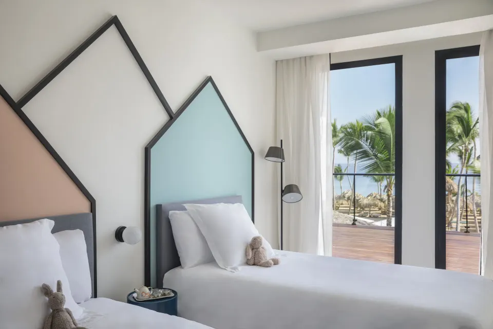 Two twin beds in a plunge pool room at Finest Punta Cana with balcony and palm views.