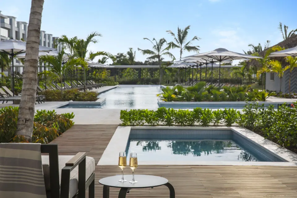 Suite terrace with plunge pool, lounge chair, and resort pool view at Finest Punta Cana.
