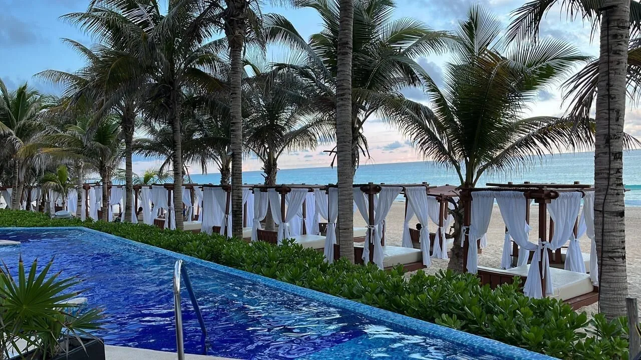 Beachfront pool with cabanas, palms, and ocean at Flamingo Cancun.