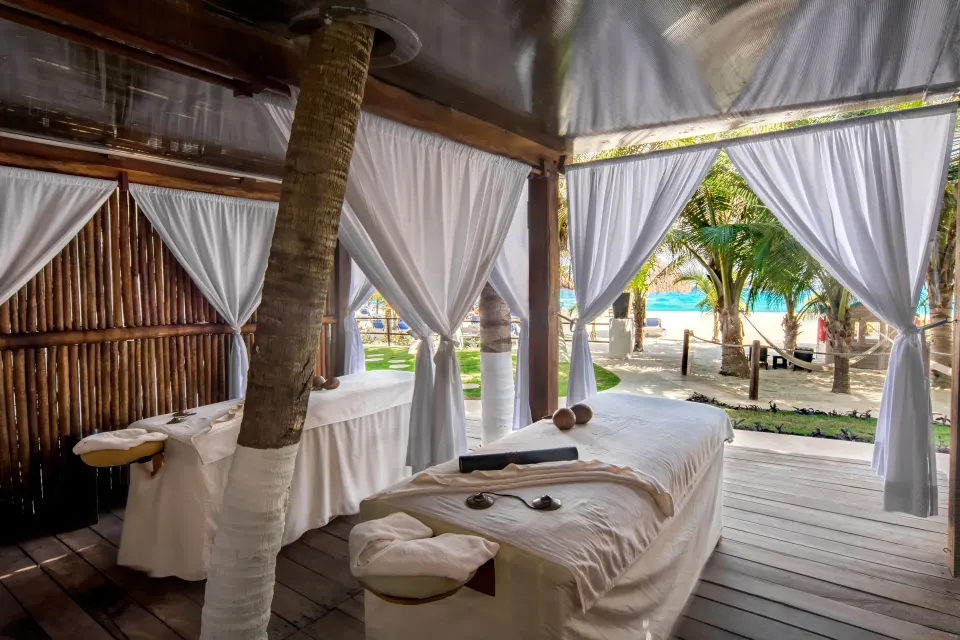 Beachside spa cabana with massage tables and white curtains at Flamingo Cancun.