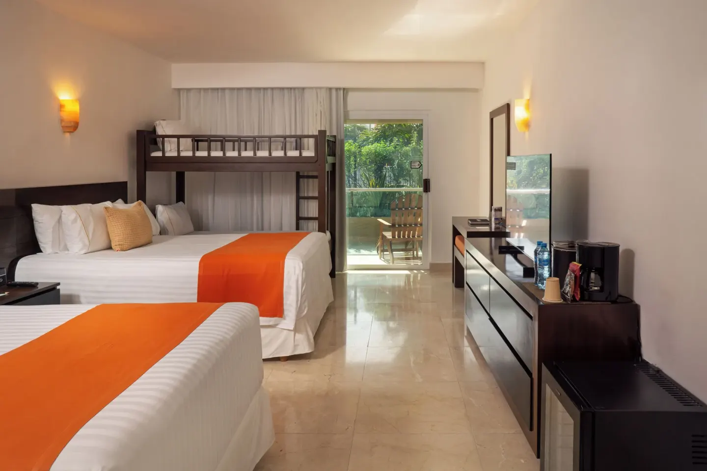 Family guest room with two beds, bunk bed, balcony, and dresser at Flamingo Cancun.