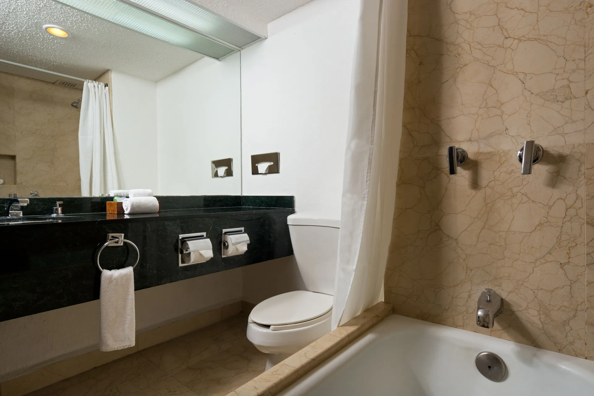Bathroom with tub, shower curtain, toilet and black vanity at Flamingo Cancun.
