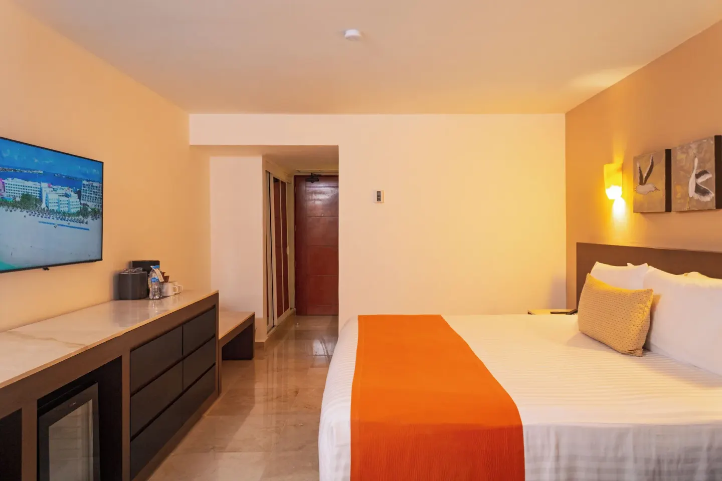 King bed guest room with TV and dresser at Flamingo Cancun.