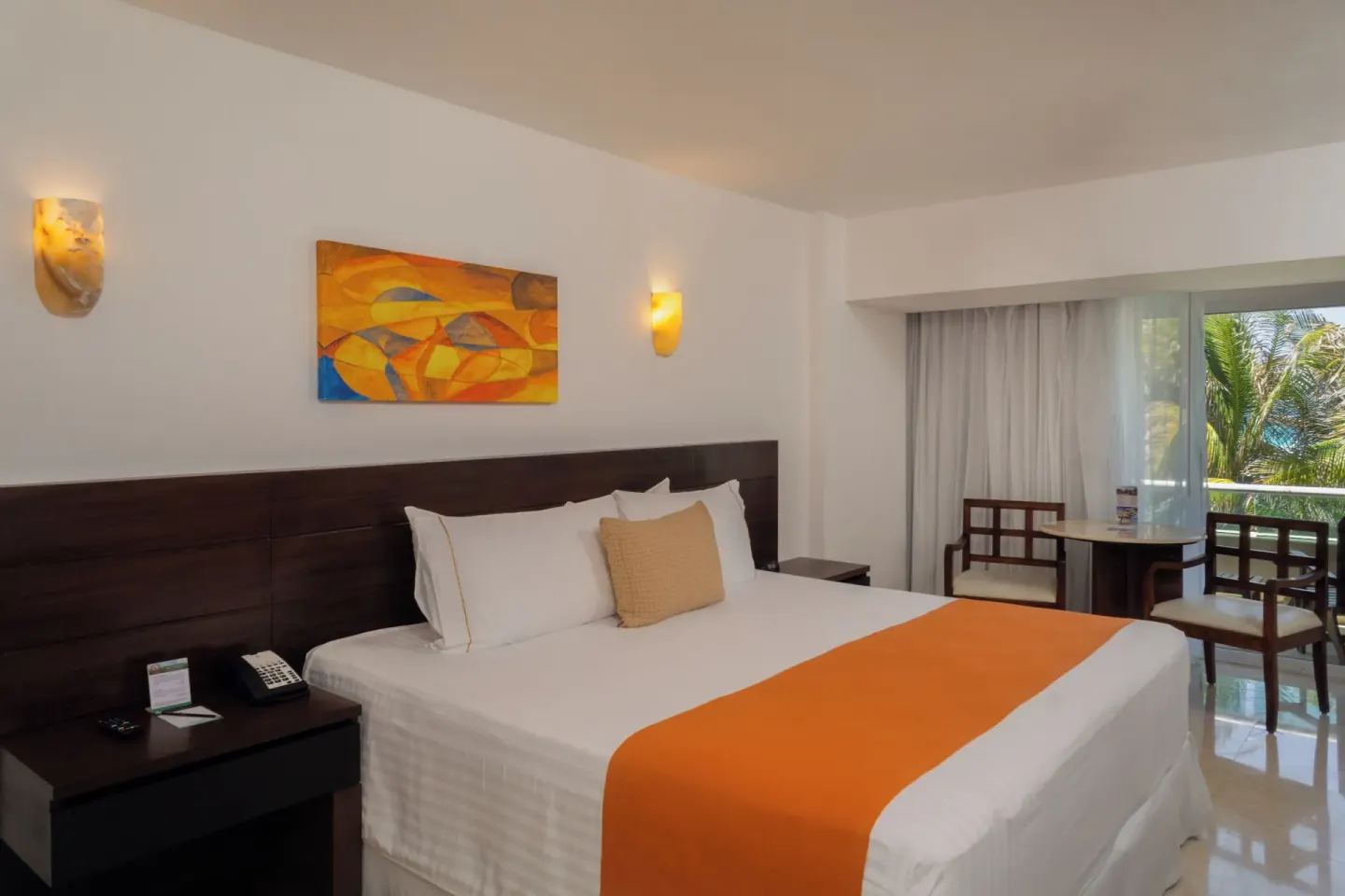 King bed guest room with table, chairs, and balcony doors at Flamingo Cancun.
