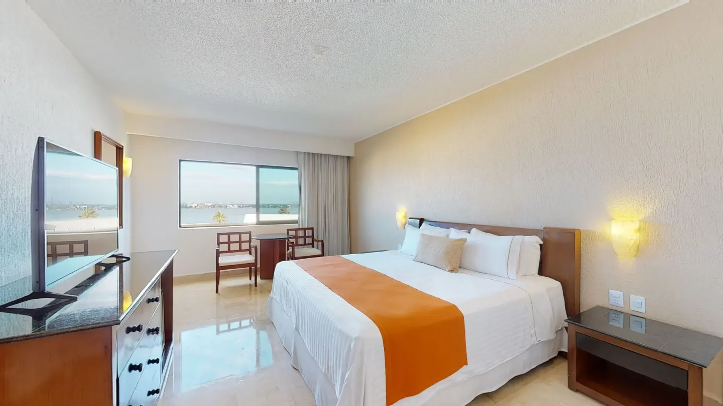 King bed guest room with lagoon view window at Flamingo Cancun.