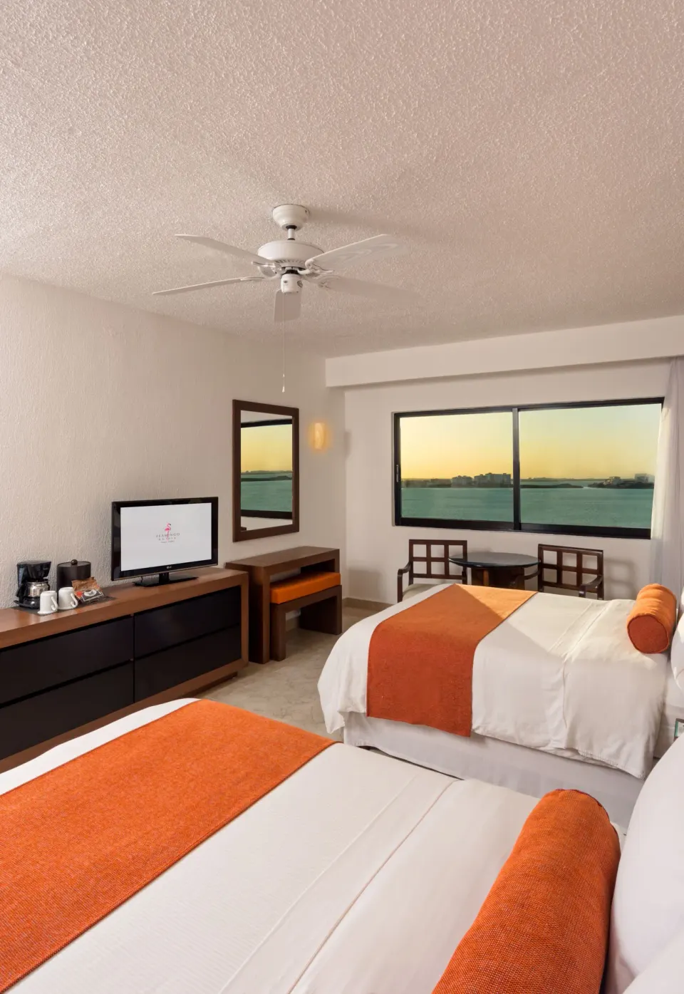 Two-bed lagoon view guest room with TV and seating at Flamingo Cancun.