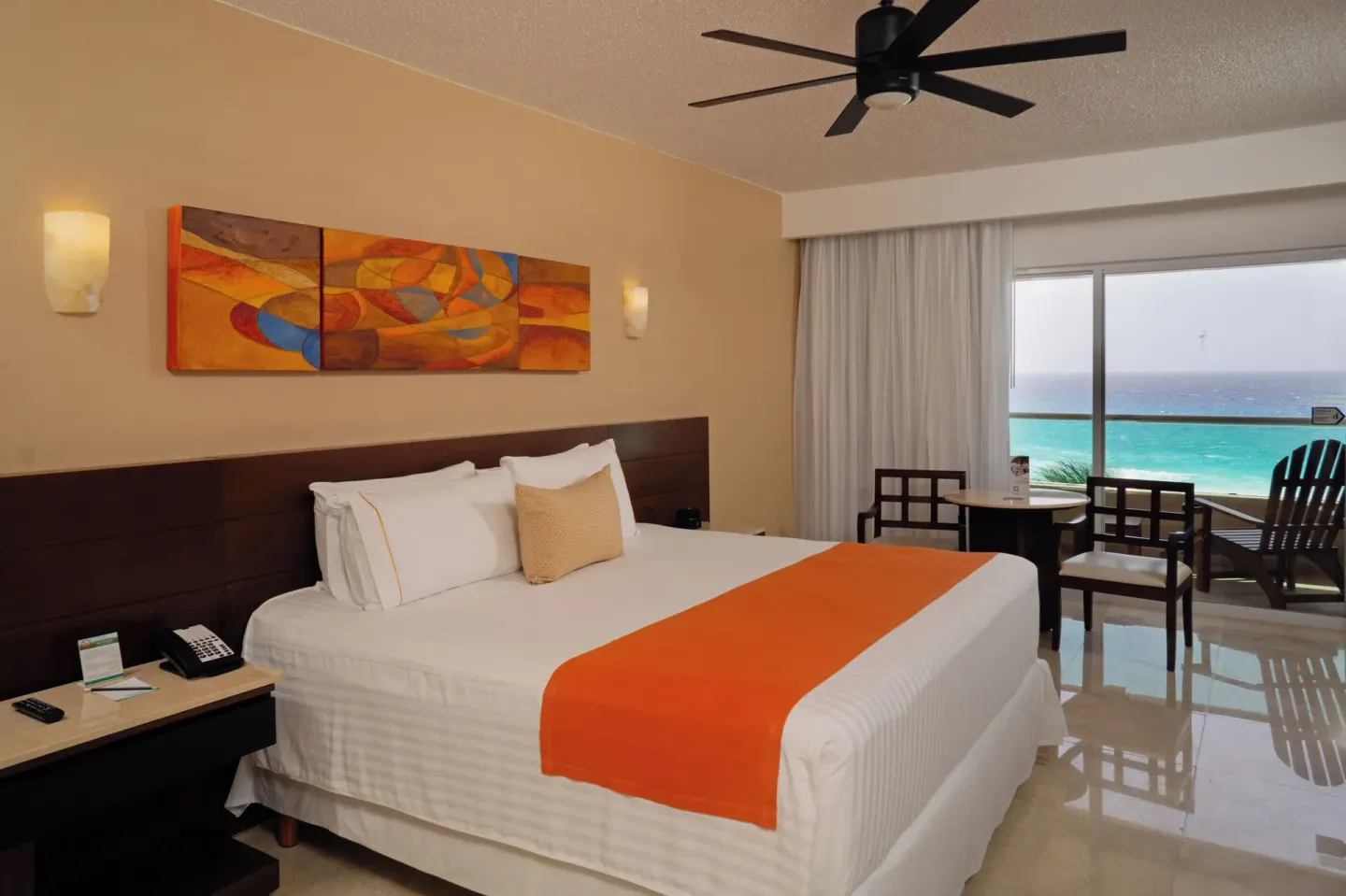 King bed ocean view guest room with balcony seating at Flamingo Cancun.