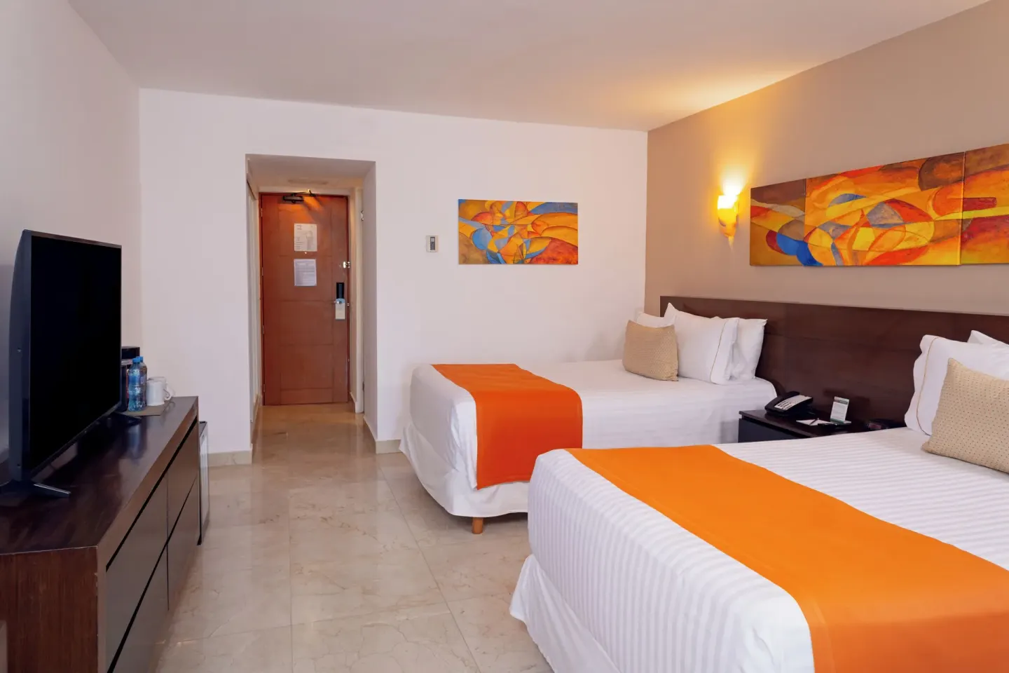 Two-bed guest room with TV, artwork, and entry door at Flamingo Cancun.