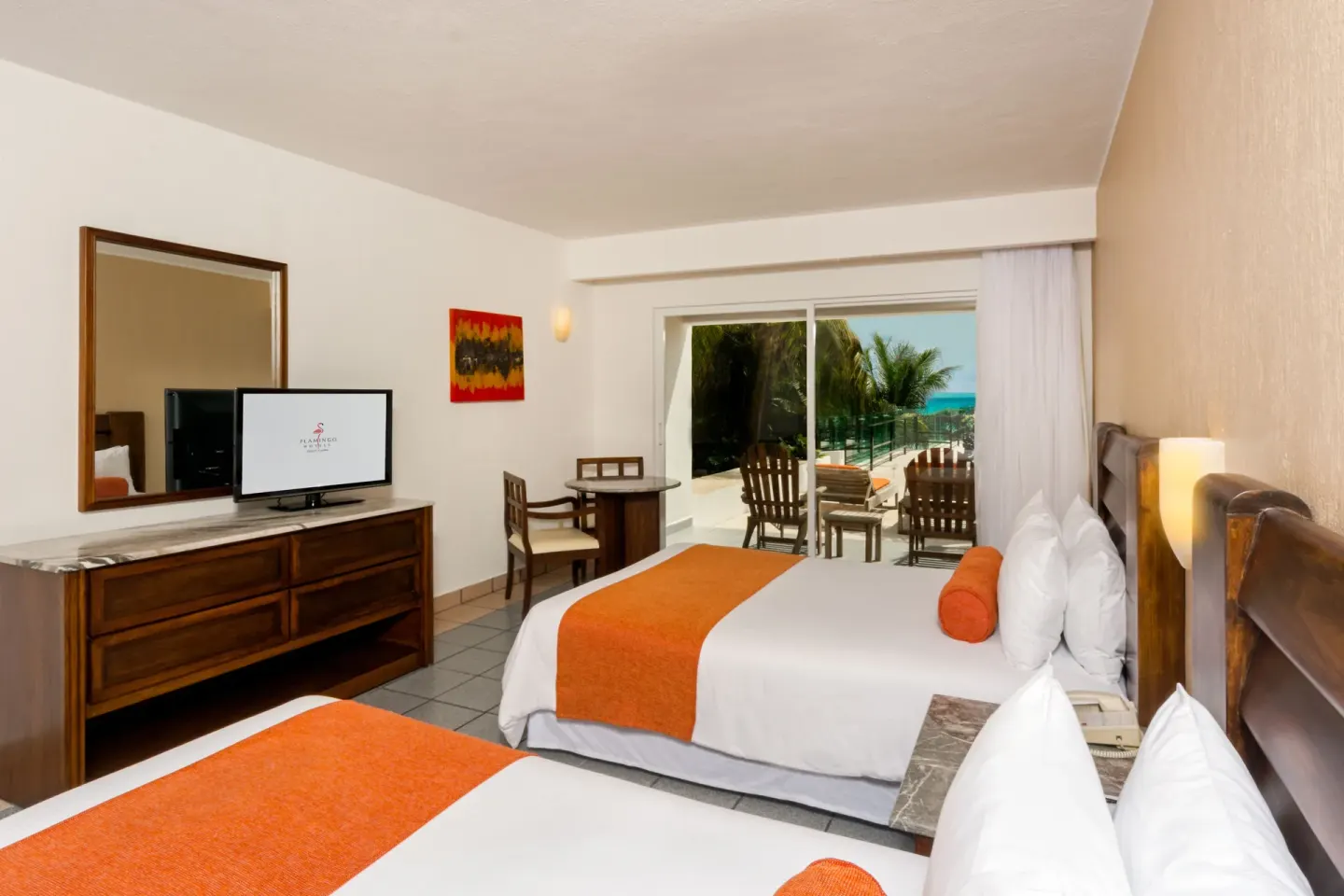 Ocean-view guest room with two beds and patio seating at Flamingo Cancun.