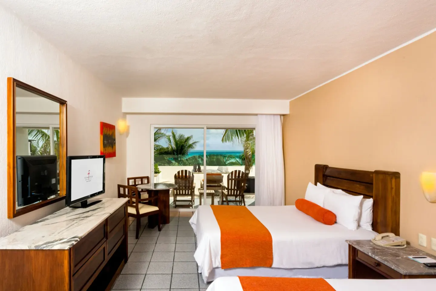 Guest room with two beds, dresser, and ocean-facing patio at Flamingo Cancun.
